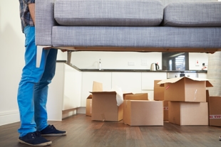 Man picking up couch with moving boxes in view - representing child custody and moving out of state