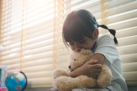 sad child hugging a teddy bear