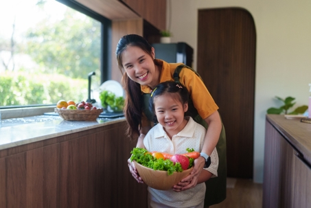 mother and daughter holding bowl of vegetables