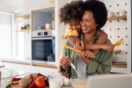 daughter hugging mother as they cook